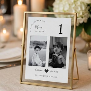 May include: A gold-framed table number card with the text "So glad you're here, When we were" and the number 1. The card features two black and white photos of children, with names "Olivia" and "James" and the date "23.3.2026".