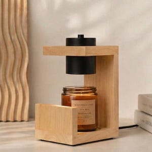 May include: A light-colored wooden candle warmer lamp featuring a C-shaped frame and a black cylindrical heating element suspended above a glass jar of scented soy wax candle with a label that reads Scented Candle Soy Wax Handmade.