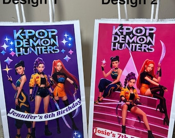 May include: Two white paper gift bags with white handles. Each bag features a colorful graphic of anime-style characters with the text "K-POP DEMON HUNTERS." One bag says "Jennifer's 6th Birthday," the other says "Josie's 7th Birthday."