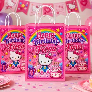 May include: Pink gift bags with white handles, featuring a rainbow, stars, and the text "Happy Birthday Fiona." Each bag showcases a cartoon cat, a cake, and gift boxes. Party supplies and decorations are visible.