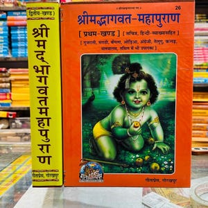 May include: A hardbound book titled Shrimadbhagwat-Mahapuran with an orange cover featuring an illustration of a young deity with green skin, a peacock feather in hair, and jewelry. The spine is yellow with black Hindi text and the Gita Press logo.