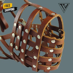 May include: A brown leather dog muzzle with a basket-like design. The muzzle has riveted accents and a sturdy construction. The image includes a logo and the words "FREE SHIPPING".