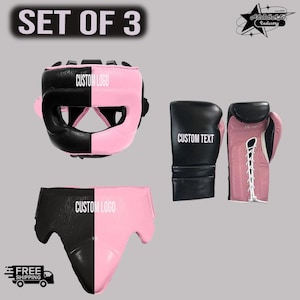 May include: A set of three boxing items featuring a black and pink color scheme. The set includes a headgear with CUSTOM LOGO text, a groin guard with CUSTOM LOGO text, and a pair of boxing gloves with CUSTOM TEXT and 14 oz printed on them.