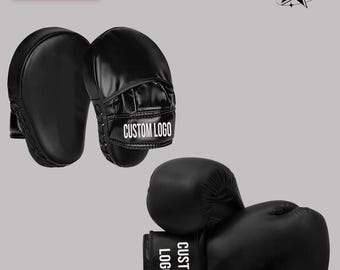 May include: A pair of black boxing mitts and a pair of black boxing gloves. The mitts and gloves have the text "CUSTOM LOGO" printed in white. The image also includes the text "SET OF 2" and a logo.
