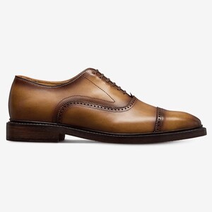May include: A single brown leather Oxford shoe with a cap toe. The shoe has a dark brown sole and heel, with decorative stitching and a lace-up closure. The leather has a polished finish and a gradient color.