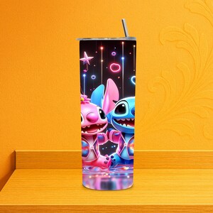 May include: A stainless steel tumbler with a cartoon illustration of two characters, one pink and one blue, set against a black backdrop with colourful lights. The tumbler has a silver straw and a black lid. A fun and colourful addition to any drinkware collection.