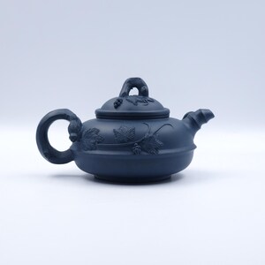 以下が含まれることがあります： 黒い持ち手と「But First, Coffee」の文字が黒い手書き風フォントで書かれた白いセラミックマグ。マグカップは白い表面に置かれています。