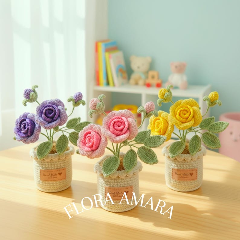 May include: Three crocheted rose arrangements in small, cream-coloured pots. Each pot features a tan label with the text Hand Made with love. The roses are purple, pink, and yellow, accompanied by green crocheted leaves and small buds.