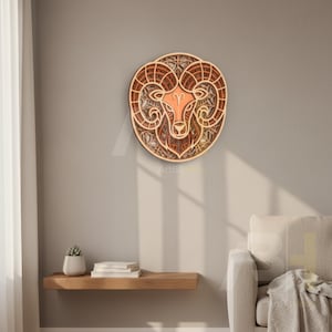 May include: A layered wooden wall art piece depicting the Aries zodiac sign. The artwork features a ram's head with intricate details and a warm color palette of browns and oranges. The piece is mounted on a neutral-colored wall.