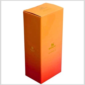 May include: A rectangular cardboard product box featuring a vertical gradient color scheme that transitions from orange at the top to red at the bottom. The box displays the Stanley logo and the text KAROL G in gold lettering on the front face.