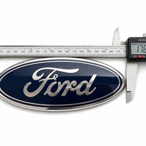 May include: A blue and silver Ford emblem is measured with a digital caliper. The emblem is oval-shaped with the word "Ford" in silver script. The caliper displays a measurement of 176.45 mm, or approximately 6.95 inches.