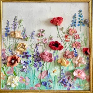 May include: A framed floral artwork featuring a textured, raised-relief design. The painting showcases a vibrant array of flowers in shades of red, pink, purple, and yellow, set against a white and green background. The artwork is enclosed in a gold frame.