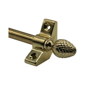May include: A gold-coloured curtain rod with a decorative pineapple-shaped finial. The rod is attached to a rectangular bracket with screw holes. The finial and bracket have a shiny, metallic finish.