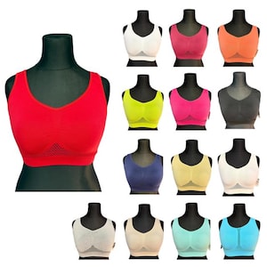 May include: A collection of seamless sports bras in various colors, including red, white, pink, orange, yellow, navy blue, and teal. Each bra is displayed on a black mannequin, showcasing the different styles and colors available. The bras have a mesh panel at the bottom.