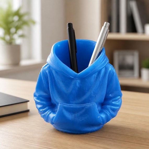 A tiny hoodie cast in mint-green resin as a pen holder — absurdly cute and genuinely unexpected on a desk.