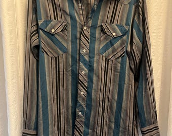 May include: A long-sleeved, blue, gray, and black striped western shirt with a button-down collar and two chest pockets. The shirt has the text "Cimarron West Ranchwear" on the label.