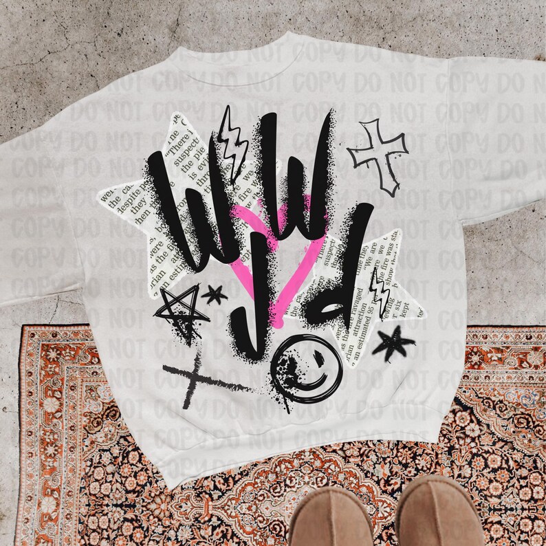 Puede incluir: Sudadera blanca con un dise&ntilde;o gr&aacute;fico que presenta las letras "WILD" en negro y rosa, junto con una cruz, rayos, estrellas y una carita sonriente. El dise&ntilde;o incorpora elementos de texto.