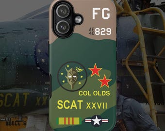 Könnte beinhalten: Eine Handyhülle mit einem Tarnmuster in Grün- und Beigetönen. Auf der Hülle stehen die Texte "FG", "AF 40 829", "COL OLDS" und "SCAT XXVII". Sie hat auch eine Teufelsgrafik und rote Sterne.