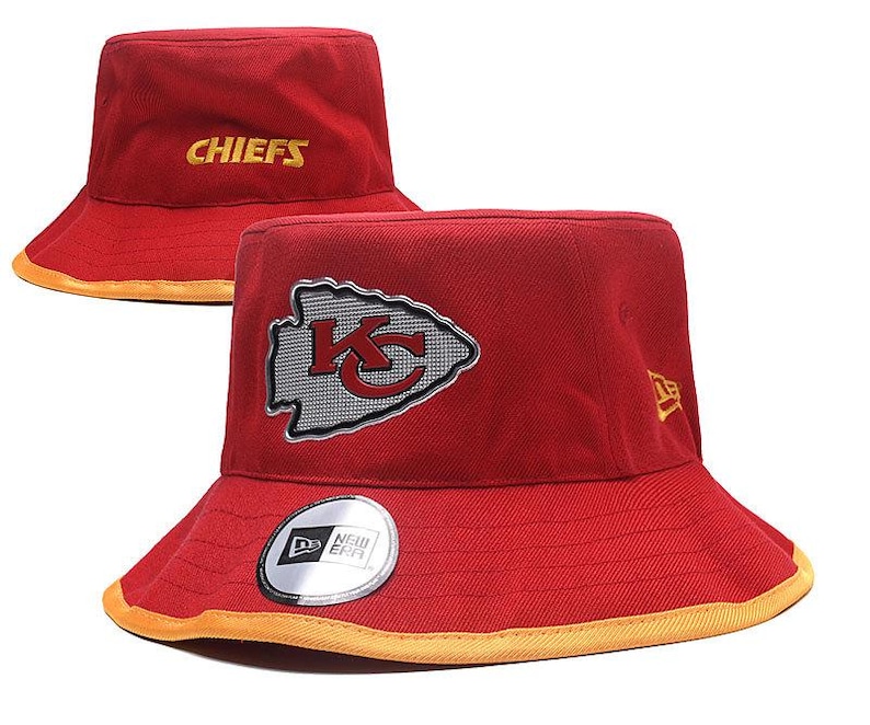 Op de afbeelding: Rode vissershoed met het woord "CHIEFS" in goud geborduurd. De hoed heeft het teamlogo op de voorkant en een New Era-sticker. De rand heeft een gouden rand.