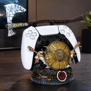 以下が含まれることがあります： 白と黒のゲームコントローラーを置くためのスタンド。台座には金色の盾、2本の交差した剣、赤いオメガのシンボルが装飾されている。青いルーン模様が施された大きな斧が、上部に水平に配置されている。
