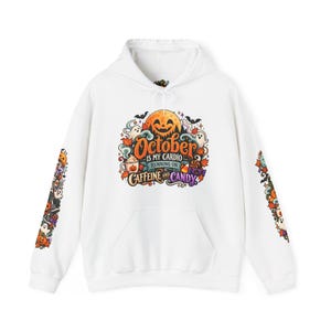 Könnte beinhalten: Ein weißer Kapuzenpullover mit einer farbenfrohen Grafik auf der Brust und den Ärmeln. Die Brustgrafik zeigt einen großen orangefarbenen Kürbiskopf, Geister, Fledermäuse und den Text "October is my cardio running on caffeine and candy" in verschiedenen Schriftarten.