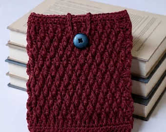 May include: A deep burgundy crochet pouch featuring a textured, raised stitch pattern. The pouch is secured with a single dark blue, four-hole button attached to a small crocheted loop at the top center, providing a simple closure for the item.