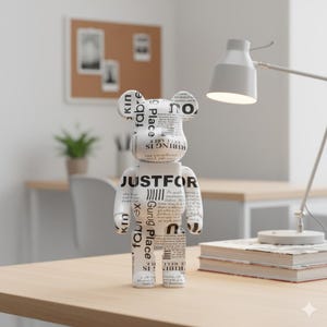 May include: A white and black decorative bear figurine with text. The bear is standing on a wooden desk, with a desk lamp and books in the background. The text on the bear includes the words "JUSTFOR" and "RIBING IS".