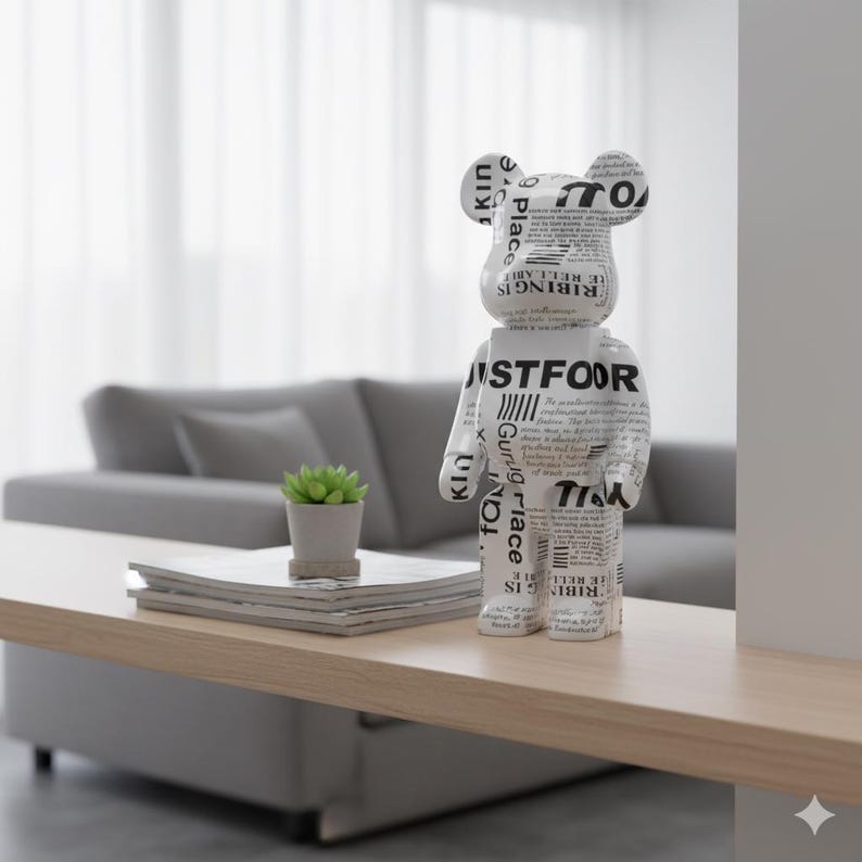 May include: A white and black bear-shaped figurine with text printed on its surface stands on a light wood table. The text includes the words "JUSTFOOR" and "RIBING IS." A small potted plant and a stack of magazines are also on the table.