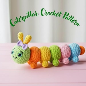 May include: A colorful, crocheted caterpillar toy with a smiling face, antennae, and a purple bow. The caterpillar is made of various colors, including green, orange, yellow, pink, and blue. The text "Caterpillar Crochet Pattern" is above the caterpillar.