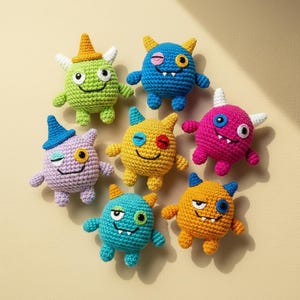 Puede incluir: Una colección de siete juguetes de monstruos de ganchillo coloridos. Cada monstruo tiene un color único, como verde, azul, morado, amarillo, rosa y naranja. Tienen cuernos, ojos y brazos y piernas pequeños. Los juguetes están dispuestos en un patrón circular.