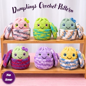 May include: Six crocheted plush dumplings with smiling faces and plastic eyes, each featuring a removable lid. The dumplings are crafted in various variegated yarn colors including pink, green, blue, purple, and yellow. Text reads Dumplings Crochet Pattern and No Sew.