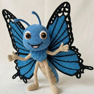 May include: A crocheted butterfly toy. It has a blue body, wings, and antennae. The wings have black edging and blue sections. The butterfly has tan arms and legs, and brown eyes. The toy is designed to look like a cartoon character.