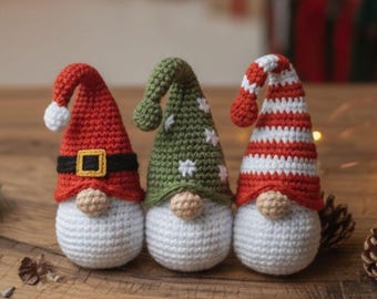 May include: Three crocheted gnomes with white bodies and various coloured hats. One has a red hat with a white bobble and black belt. Another has a green hat with white stars. The third has a red and white striped hat.