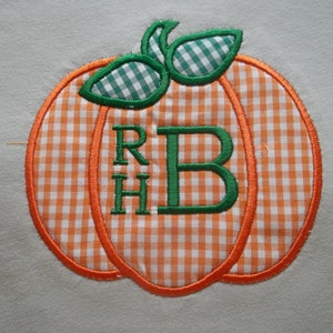 May include: A gingham pumpkin with an orange outline and green leaves. The letters "RH" and "B" are embroidered in green on the pumpkin.