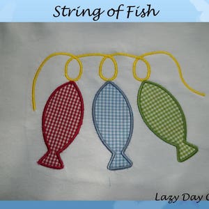 May include: A string of three embroidered fish, one red and white, one blue and white, and one green and white, hanging on a yellow string. The text "Lazy Day Crafts" is at the bottom of the image.