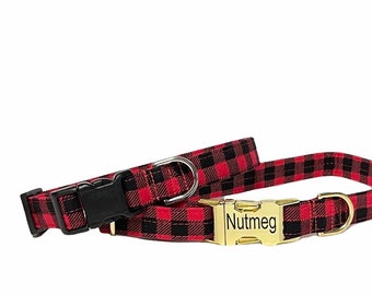 May include: A red and black buffalo plaid pet collar featuring a gold-toned metal side-release buckle engraved with the name Nutmeg. The collar includes a matching gold-toned D-ring for leash attachment and an adjustable black plastic slider.