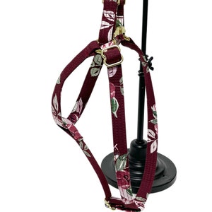 Peut inclure: Harnais pour chien floral bordeaux avec des ferrures dor&eacute;es. Le harnais est fait d'un tissu doux et confortable et pr&eacute;sente un imprim&eacute; floral.