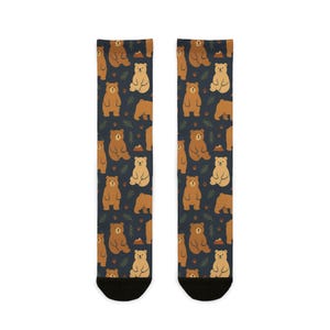 May include: A pair of socks with a navy blue background and a repeating pattern of brown bears, green trees, and orange mountains. The bears are in various poses. The socks have black toes and heels.