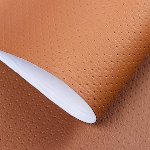Peut inclure: Gros plan sur une feuille de cuir marron perforé. Le cuir a une surface texturée avec de petits trous espacés uniformément. Le bord de la feuille est recourbé, révélant un dessous blanc.