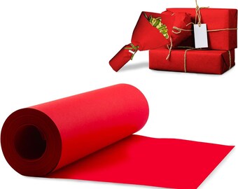 Può includere: Un rotolo di carta rosso brillante si srotola su una superficie piana. Sullo sfondo, ci sono tre scatole regalo rosse avvolte, legate con spago e un mazzo di fiori avvolto in carta rossa. Un'etichetta bianca vuota è attaccata a uno dei regali.