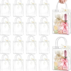 Puede incluir: Bolsas de regalo transparentes con asas plateadas y lazos de cinta blancos. Algunas están vacías, otras contienen un osito de peluche, una botella de champán rosa y caramelos, perfectas para un regalo.