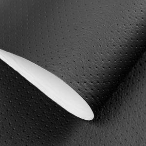 Puede incluir: Primer plano de un rollo de material de cuero negro perforado. El cuero tiene una superficie texturizada con pequeños agujeros espaciados uniformemente. Se ve una sección de material blanco, que contrasta con el cuero negro.