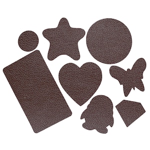 May include: A selection of brown leather shapes, including a circle, star, heart, butterfly, rectangle, and a penguin-like figure. The cutouts have a textured surface and are set against a white backdrop.