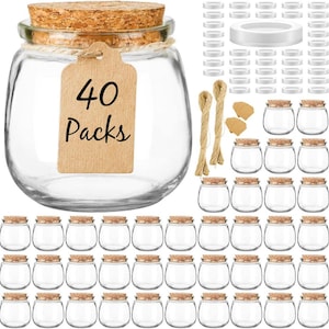 Può includere: Una collezione di piccoli barattoli di vetro trasparente con coperchi in sughero. Un barattolo ha un'etichetta con la scritta "40 Packs". I barattoli sono disposti in file, con coperchi e spago aggiuntivi. Adatto per artigianato, conservazione o scopi decorativi.