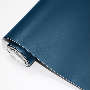 May include: A roll of navy blue faux leather material. The material has a textured surface and is rolled up, revealing a white backing. The roll is positioned diagonally against a white background, showcasing the color and texture.