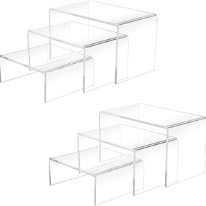 May include: Clear acrylic display risers in a stepped design. Each set includes three platforms of varying sizes, perfect for showcasing products. The transparent material allows for a clean, modern aesthetic, ideal for retail or home use.