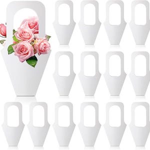 Può includere: Cestino di fiori di carta bianco con manico, pieno di rose rosa. Sono visibili anche dieci cestini di fiori di carta bianchi aggiuntivi con manici. Le rose hanno foglie verdi.