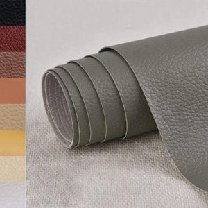 May include: A roll of gray faux leather with a textured surface. The image also shows a color swatch of various faux leather colors, including black, red, brown, tan, beige, yellow, and white.