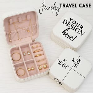 May include: White jewelry travel case with pink interior, open to display gold jewelry. The case is 4 inches by 4 inches (10 cm x 10 cm) and 2 inches (5 cm) deep. The lid has the text "YOUR DESIGN here!"