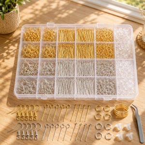 May include: A clear plastic organizer filled with various jewelry-making supplies. The compartments contain gold and silver-colored earring hooks, head pins, eye pins, jump rings, and other components. Additional gold and silver findings are arranged below the organizer.
